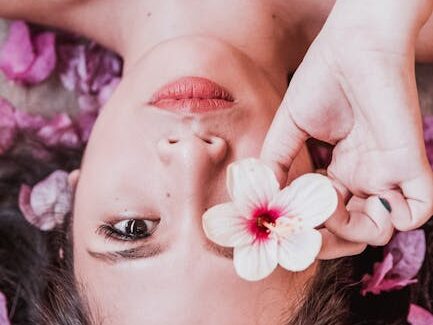 Elegant photoshoot featuring a woman holding a pink flower amidst petals.